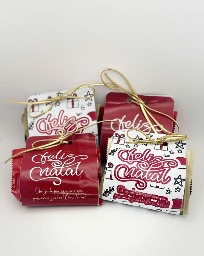 Lembrancinhas de Natal embaladas com tag Feliz Natal e laço dourado